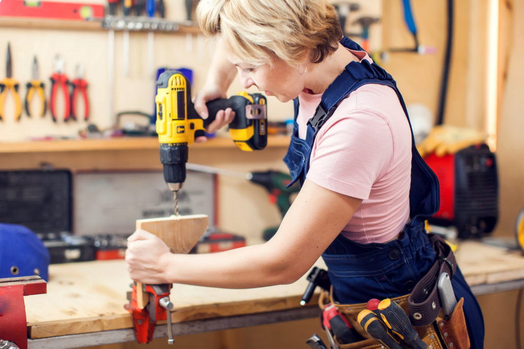 Young handy woman with short blond hair working with screwdriver.